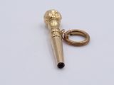 a small gold microphone charm on a white surface