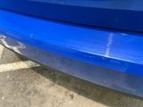 a close up of a blue car parked in a parking lot