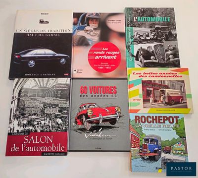 several books on a table with a red car in the background