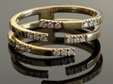 two gold rings with diamonds on top of a black surface
