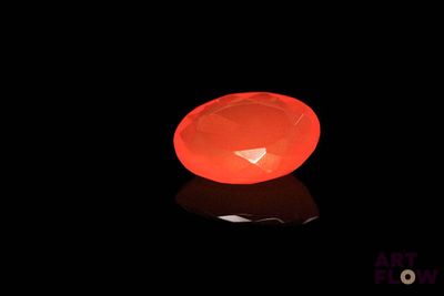 a glowing orange object in the dark with a reflection on the ground