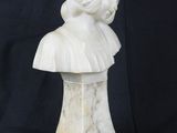 white marble bust of a woman with a hat on a black background