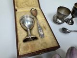 a silver cup and spoon in a case on a table