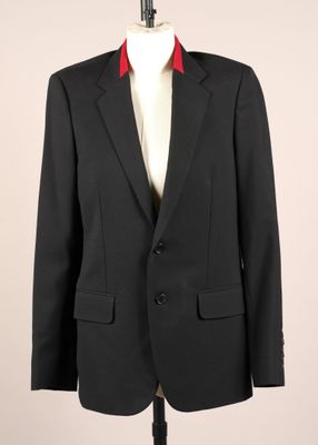 un costume noir orné de passementeries rouges sur un mannequin