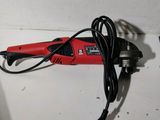 a red and black electric tool sitting on a counter