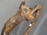 someone is holding a wooden walking stick with a dog head on it
