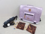un sac violet contenant un sèche-cheveux et d'autres objets, posé sur une table