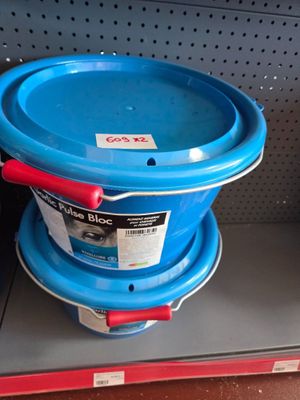 a blue bucket with a red handle sitting on a shelf
