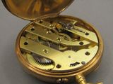 une montre de poche en or posée dessus, sur une table