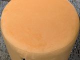 yellow round foot stool sitting on the floor next to a cardboard box