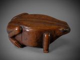 an old wooden frog figurine sitting on top of a table
