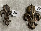 deux fleurs de lys en métal posées sur une table, accompagnées d'une étiquette de prix
