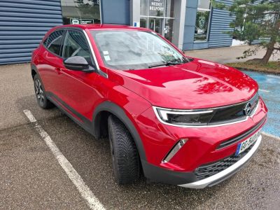 Le SUV rouge est garé devant un immeuble bleu.
