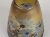 a yellow vase with blue flowers on it on a white surface