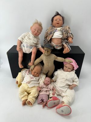 five baby dolls sitting next to each other on a black box