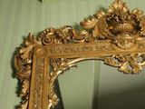 a mirror with a gold frame on a green wall