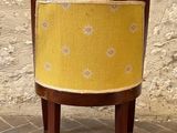 a small chair with a yellow seat on a brick floor
