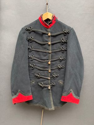 une vieille veste militaire accrochée au mur à côté d'un cintre en bois