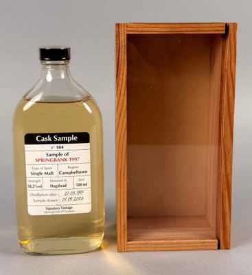 une photo montrant une bouteille d'alcool posée devant une caisse en bois
