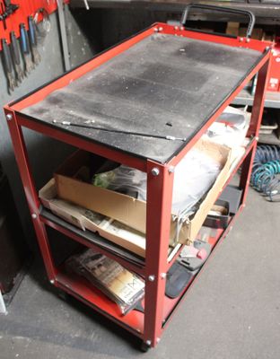 a red work cart with tools on it in a garage