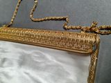 an image of a gold purse sitting on top of a white sheet