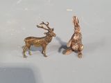 two figurines of a rabbit and a deer on a white surface