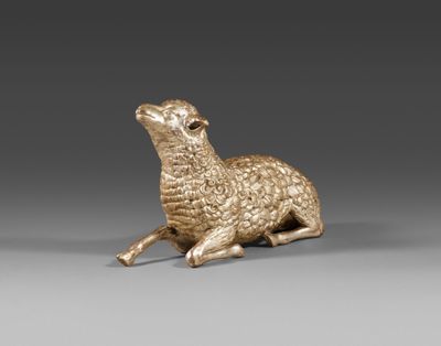 une figurine dorée représentant un mouton sur fond gris