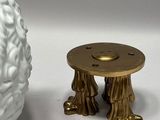 a white vase with a gold base next to a white vase with a gold base