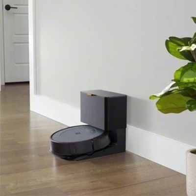 a robot that is sitting on the floor next to a potted plant