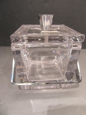 une boîte en verre transparent avec un couvercle argenté, posée sur une table