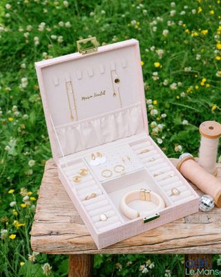 a small pink box with jewelry on a wooden table