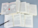 several open books and a pen on a table with a map