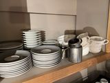 many plates and cups on a shelf in the kitchen