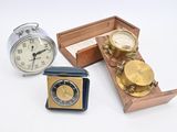 trois horloges et une boîte de pièces de monnaie posées sur une surface blanche