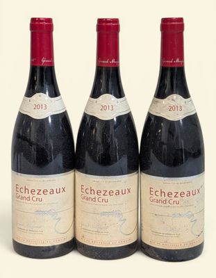 trois bouteilles de vin rouge posées l'une à côté de l'autre sur une surface blanche