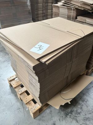 Plusieurs piles de cartons sont empilées sur une palette dans un entrepôt