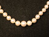 a close up of a necklace with pearls on a black surface