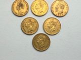 six british gold sovereigns on a white surface