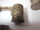 a small brass lighter sitting on a table next to a cup