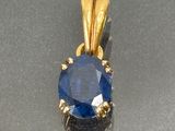 an image of a blue sapphire and diamond pendant on a silver surface