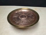 a gold plate on a table with a black background