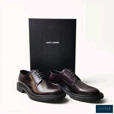 men ' s brown leather shoes in front of a black box on a white background