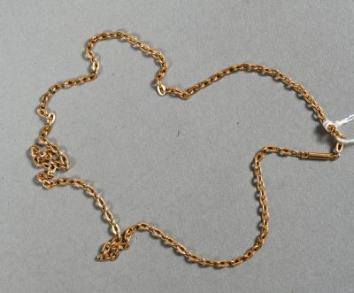 un gros plan d'un collier en or avec une chaîne posé sur une surface grise