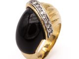 a close up of a gold ring with a black stone and diamonds