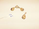 two pairs of gold earrings are shown on a white surface