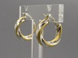 boucles d'oreilles créoles bicolores or et argent, présentées sur un présentoir transparent