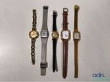 quatre montres différentes sont alignées sur une surface blanche