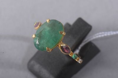 a close up of a ring with a green stone surrounded by garnetts