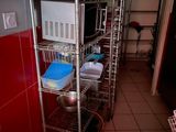 une étagère métallique sur laquelle sont posés de la vaisselle et des casseroles, dans une cuisine