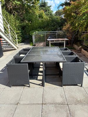 une table et des chaises sur une terrasse, avec un escalier en arrière-plan